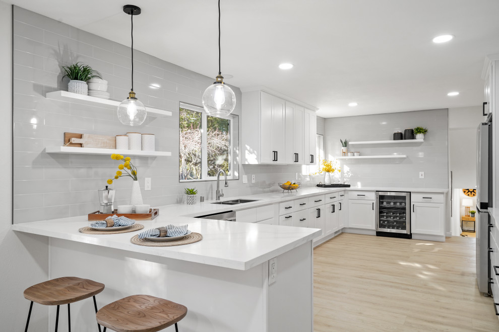 This is an example of a modern kitchen in San Francisco with quartzite benchtops, grey splashback, stainless steel appliances, beige floor and white benchtop.