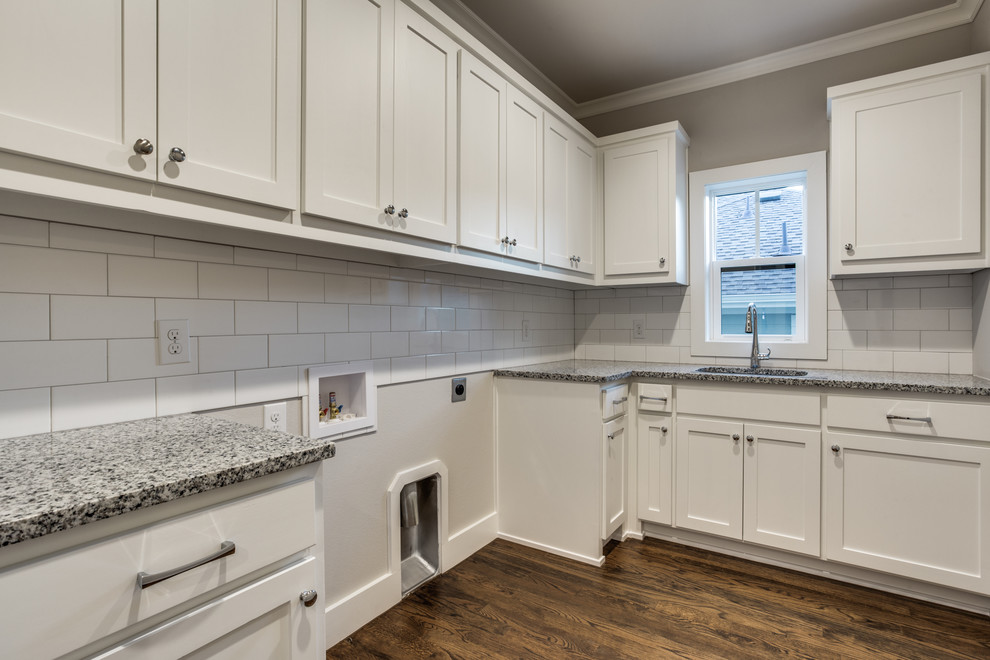 This is an example of a mid-sized country l-shaped utility room in Dallas with shaker cabinets, white cabinets, subway tile splashback, an undermount sink, granite benchtops, grey walls, dark hardwood floors and a side-by-side washer and dryer.
