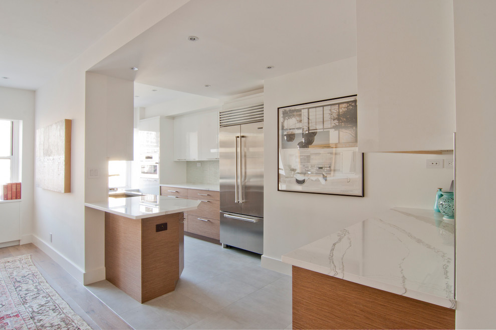 Photo of a mid-sized contemporary galley open plan kitchen in New York with an undermount sink, flat-panel cabinets, white cabinets, marble benchtops, stainless steel appliances, ceramic floors, no island and white floor.