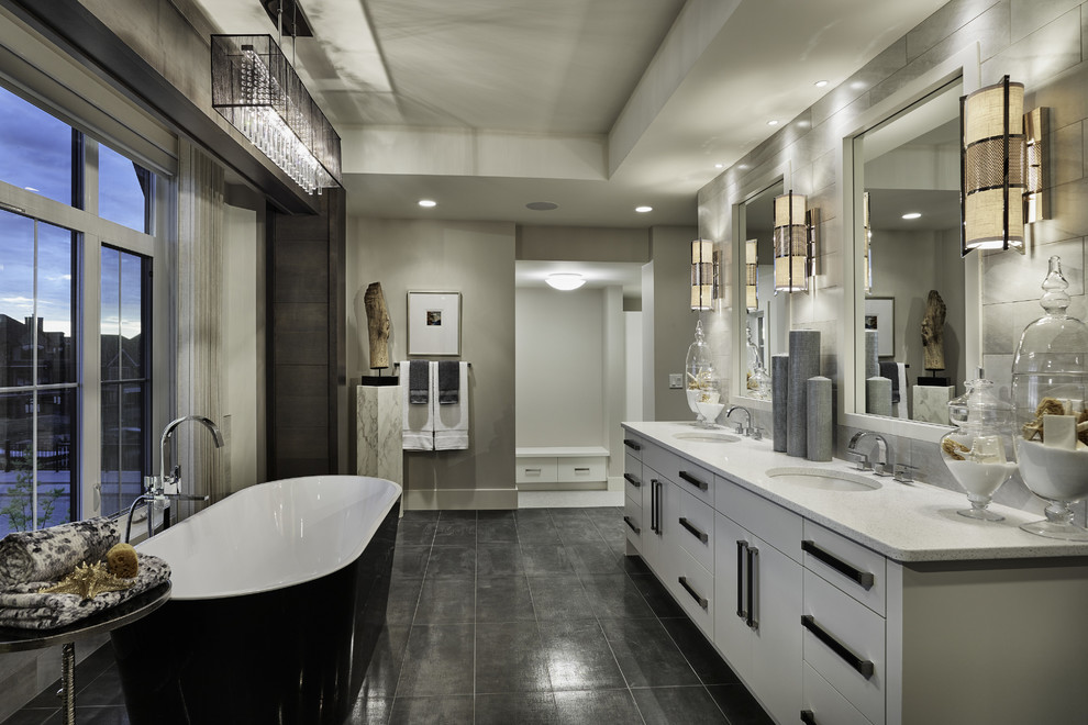 This is an example of a mid-sized transitional master bathroom in Calgary with an undermount sink, flat-panel cabinets, white cabinets, a freestanding tub, gray tile, slate, grey walls, concrete floors, engineered quartz benchtops, grey floor and grey benchtops.