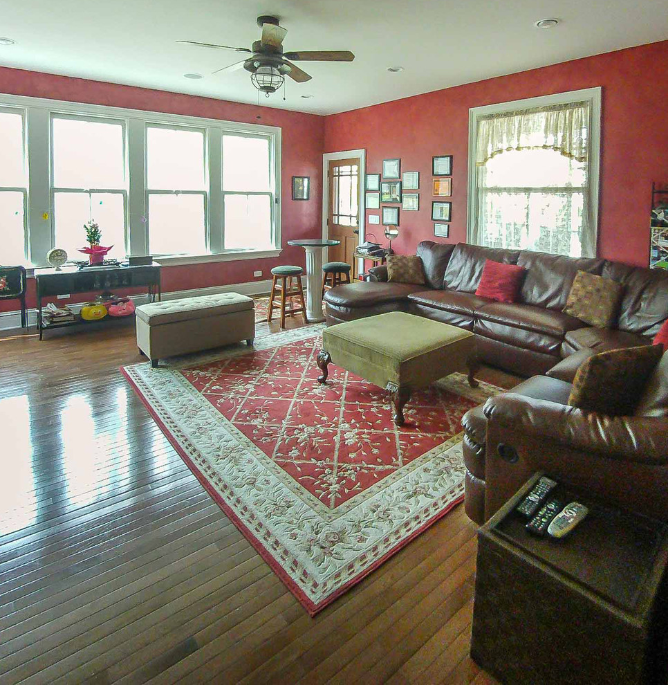 Photo of a mid-sized traditional formal open concept living room in Chicago with red walls, medium hardwood floors, a standard fireplace, a wood fireplace surround, a wall-mounted tv, brown floor, wallpaper and wallpaper.
