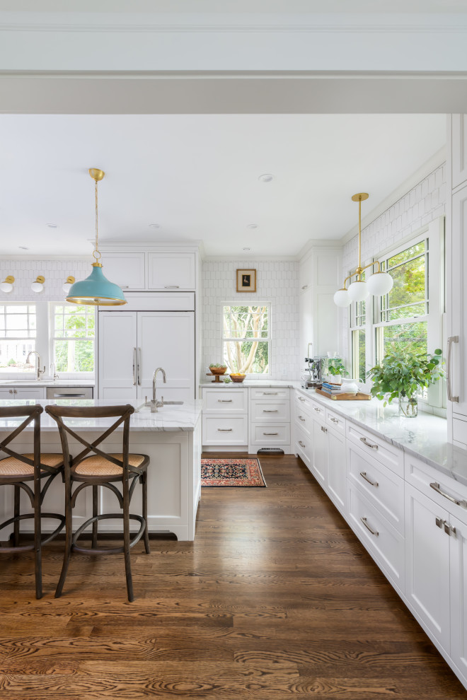 Eat-in kitchen - large coastal galley dark wood floor and brown floor eat-in kitchen idea in Atlanta with an undermount sink, shaker cabinets, white cabinets, quartzite countertops, white backsplash, marble backsplash, paneled appliances, an island and white countertops