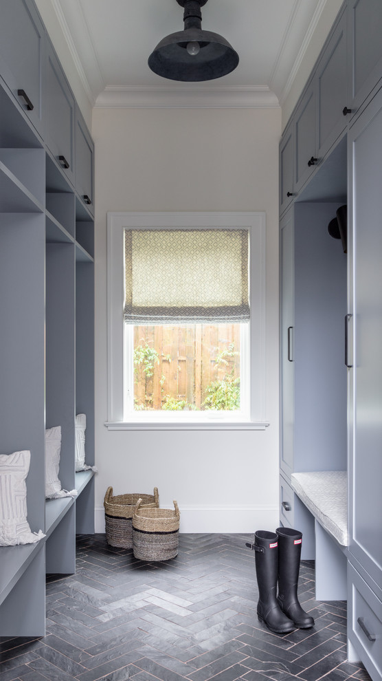 This is an example of a transitional mudroom in New York with white walls and black floor.