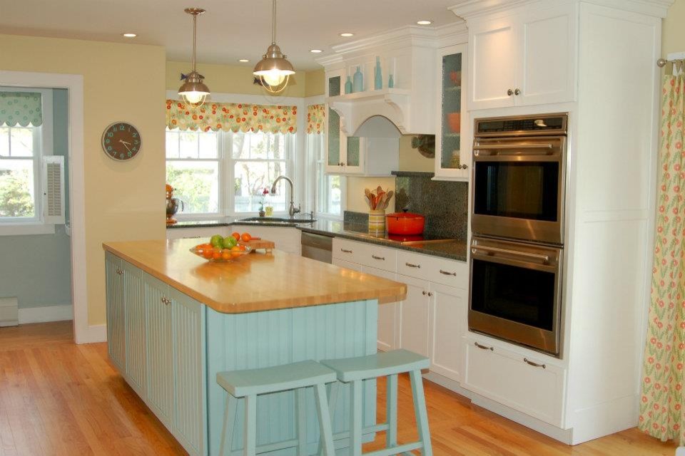 This is an example of a beach style kitchen in Boston with an undermount sink, recessed-panel cabinets, turquoise cabinets, wood benchtops, stone slab splashback, stainless steel appliances, light hardwood floors and with island.
