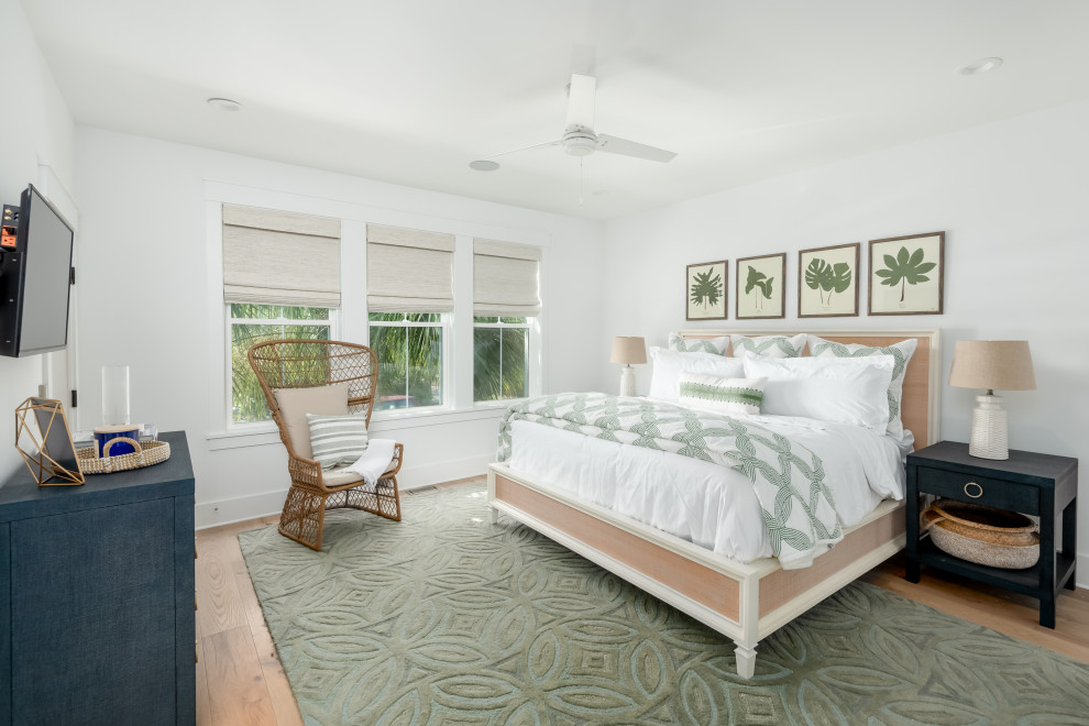 Large tropical master bedroom in Charleston with white walls, light hardwood floors and green floor.