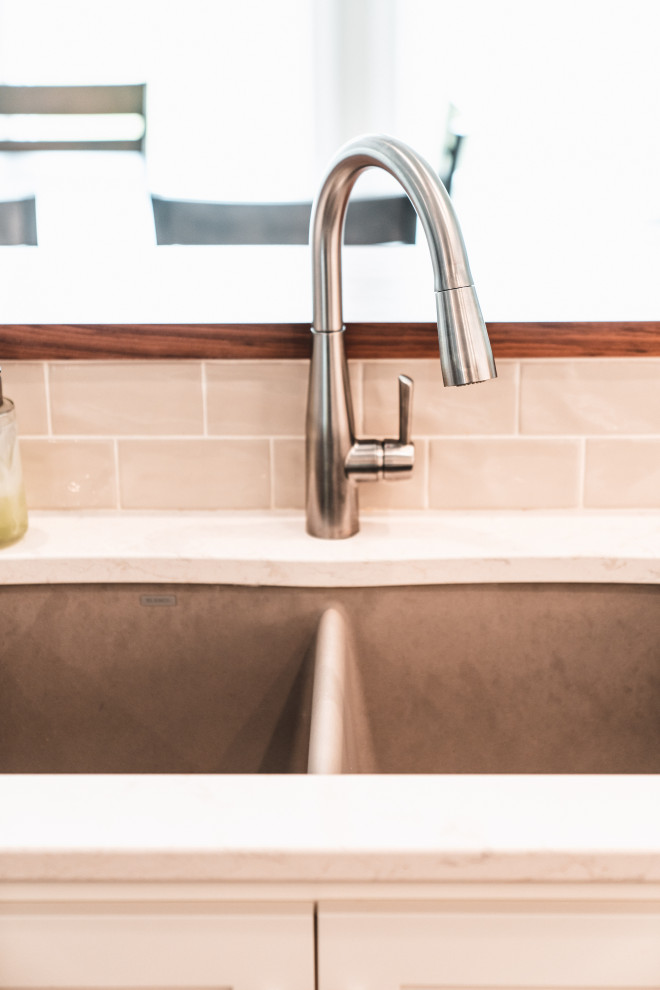 Inspiration for a large transitional l-shaped vinyl floor and brown floor kitchen pantry remodel with an undermount sink, shaker cabinets, white cabinets, quartz countertops, gray backsplash, subway tile backsplash, stainless steel appliances, an island and white countertops