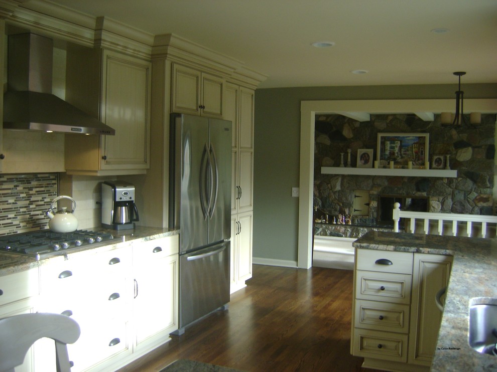 Photo of a traditional kitchen in Detroit with an undermount sink, white cabinets, granite benchtops, multi-coloured splashback, stainless steel appliances and medium hardwood floors.