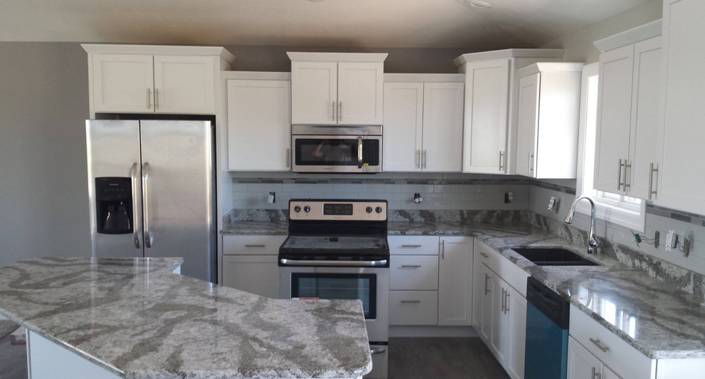 Large transitional l-shaped eat-in kitchen photo with an undermount sink, shaker cabinets, white cabinets, granite countertops, white backsplash, porcelain backsplash, stainless steel appliances and an island