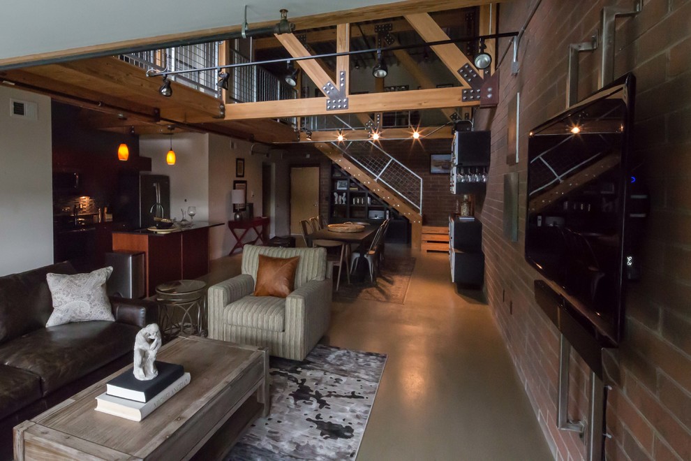 This is an example of an industrial loft-style living room in Detroit with concrete floors and a wall-mounted tv.