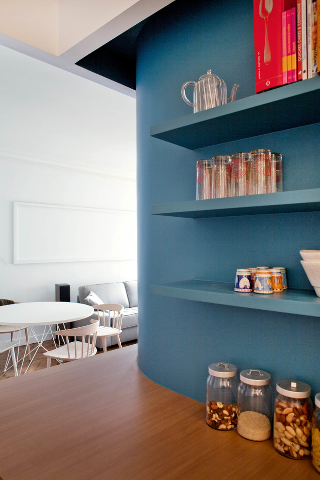 Réalisation d'une salle à manger ouverte sur le salon design avec un mur bleu, parquet foncé et un sol marron.