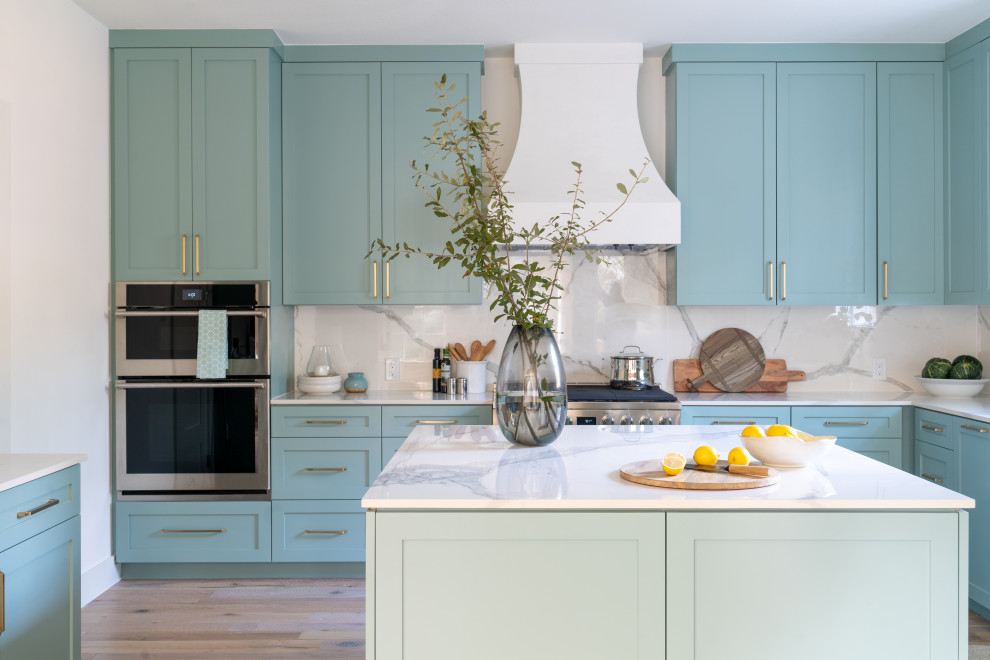 Transitional u-shaped medium tone wood floor and brown floor kitchen photo in Austin with shaker cabinets, blue cabinets, white backsplash, stone slab backsplash, an island and white countertops