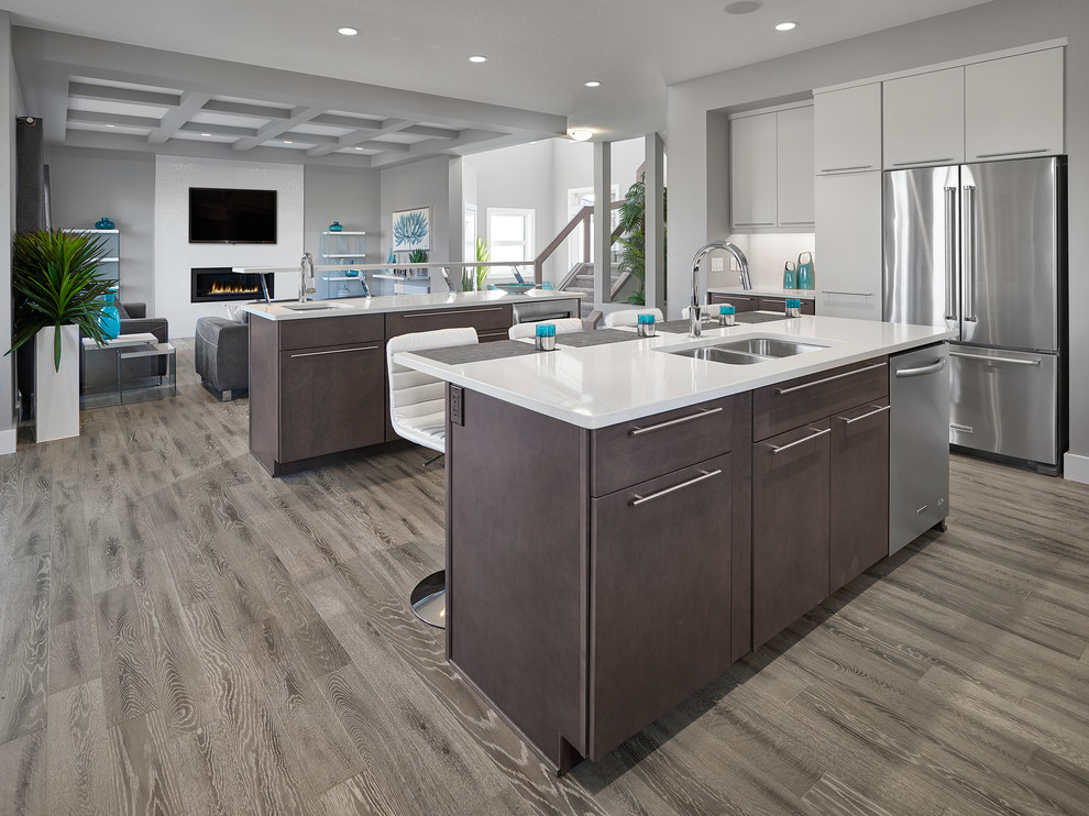 Mid-sized transitional light wood floor kitchen photo in Edmonton with an undermount sink, flat-panel cabinets, white cabinets, quartzite countertops, white backsplash, ceramic backsplash, stainless steel appliances and two islands