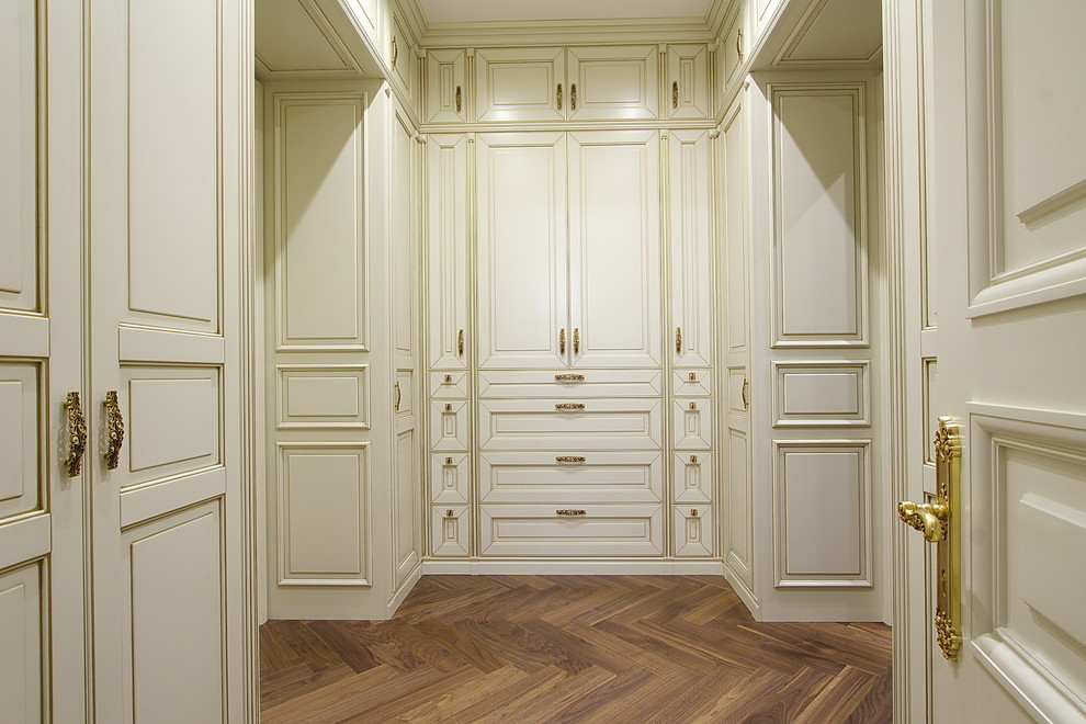 Mid-sized traditional gender-neutral built-in wardrobe in Saint Petersburg with raised-panel cabinets, light wood cabinets and dark hardwood floors.