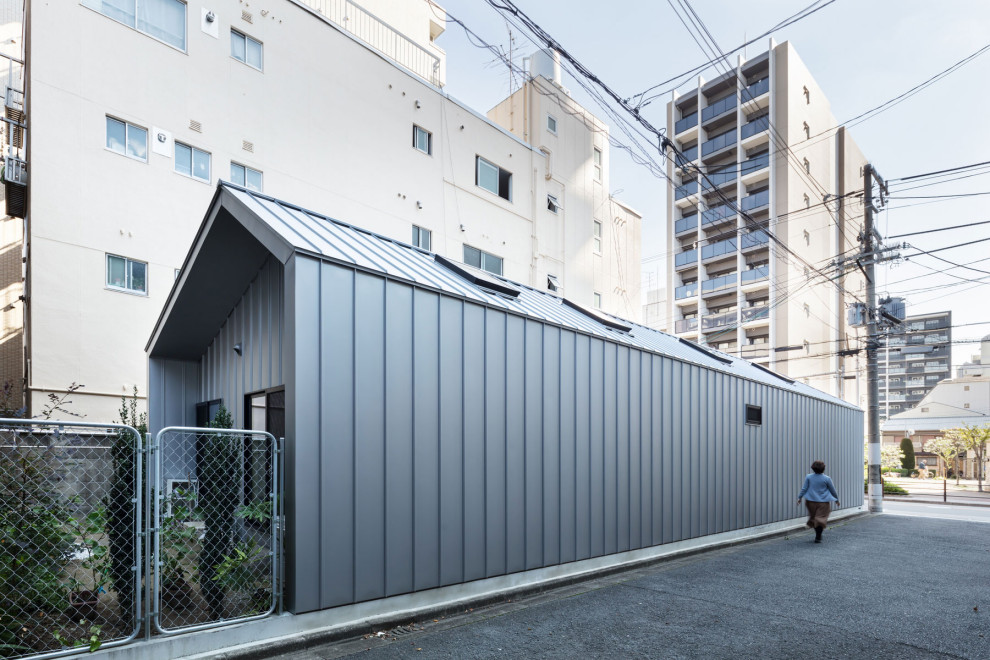 Photo of a small industrial one-storey grey house exterior in Osaka with metal siding, a gable roof, a metal roof and a grey roof.