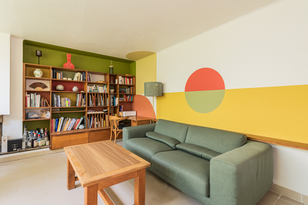 Пример оригинального дизайна: открытая гостиная комната среднего размера с с книжными шкафами и полками, желтыми стенами, бетонным полом, стандартным камином и бежевым полом без телевизора