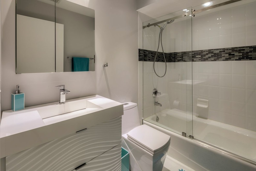 Photo of a mid-sized modern bathroom in Miami with a drop-in tub, a shower/bathtub combo, a one-piece toilet, white tile and white walls.