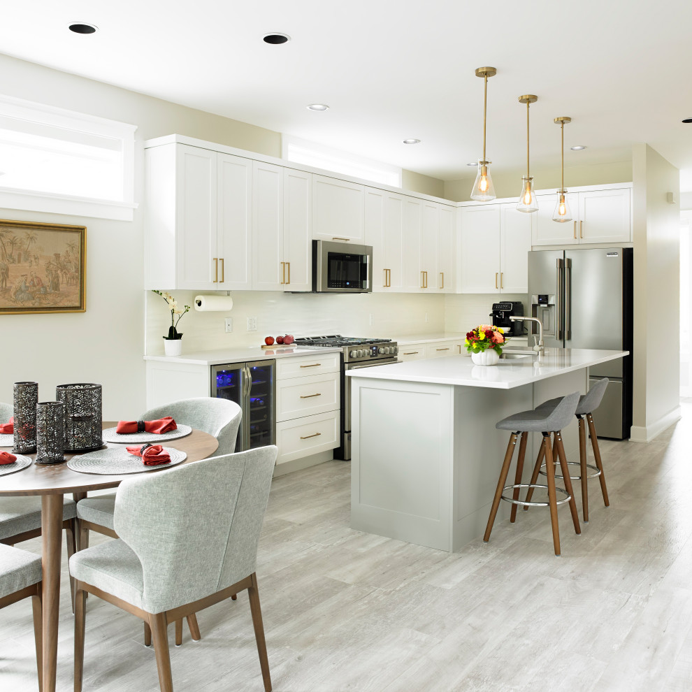 Mid-sized transitional l-shaped beige floor open concept kitchen photo with an undermount sink, shaker cabinets, white cabinets, quartz countertops, white backsplash, ceramic backsplash, stainless steel appliances and an island