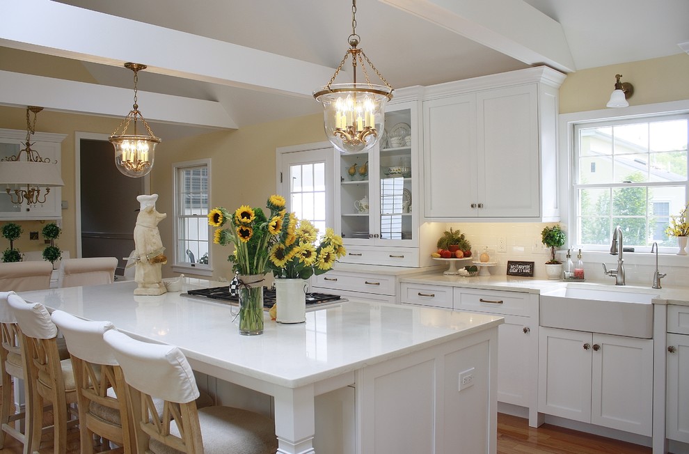 This is an example of a large transitional l-shaped eat-in kitchen in Philadelphia with a farmhouse sink, shaker cabinets, white cabinets, quartz benchtops, white splashback, ceramic splashback, stainless steel appliances, light hardwood floors and with island.