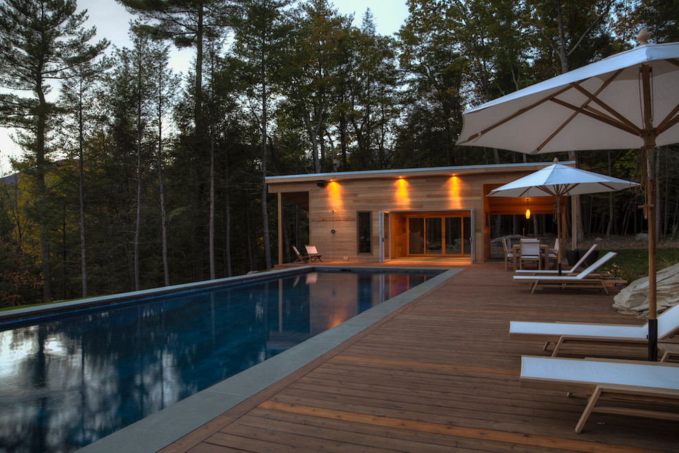 Inspiration for a mid-sized modern side yard rectangular lap pool in New York with a pool house and decking.