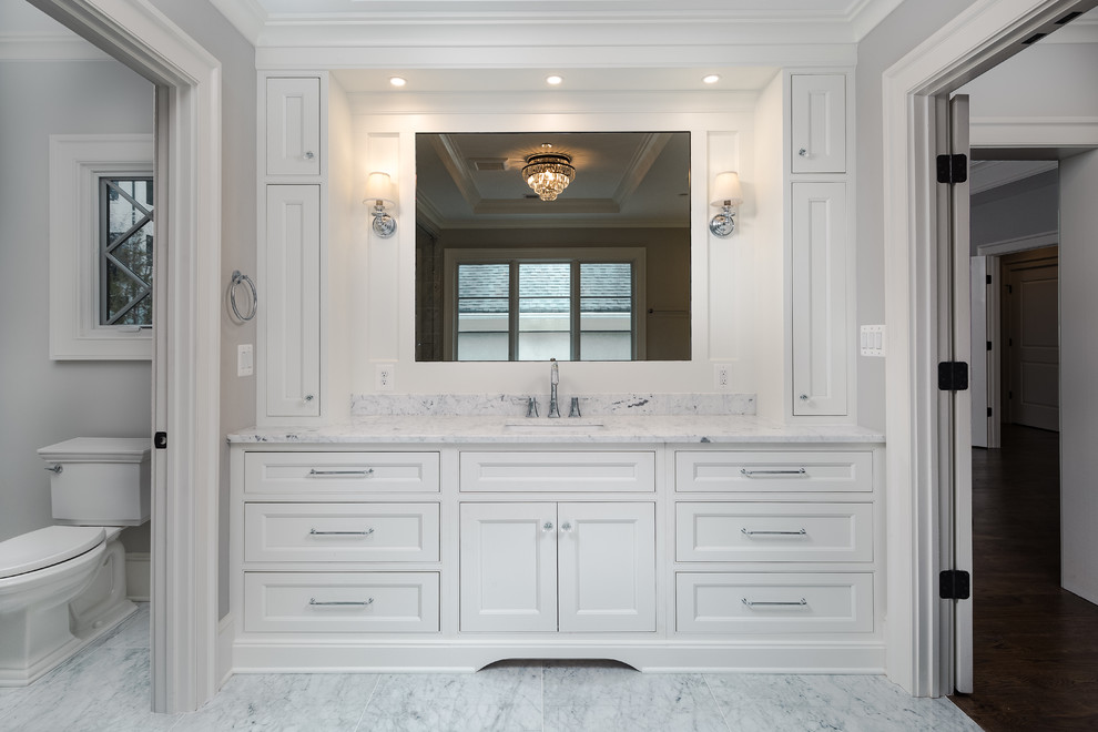 This is an example of a large transitional master wet room bathroom in DC Metro with recessed-panel cabinets, white cabinets, a freestanding tub, a two-piece toilet, multi-coloured tile, marble, grey walls, marble floors, an undermount sink, marble benchtops, multi-coloured floor, a hinged shower door and multi-coloured benchtops.