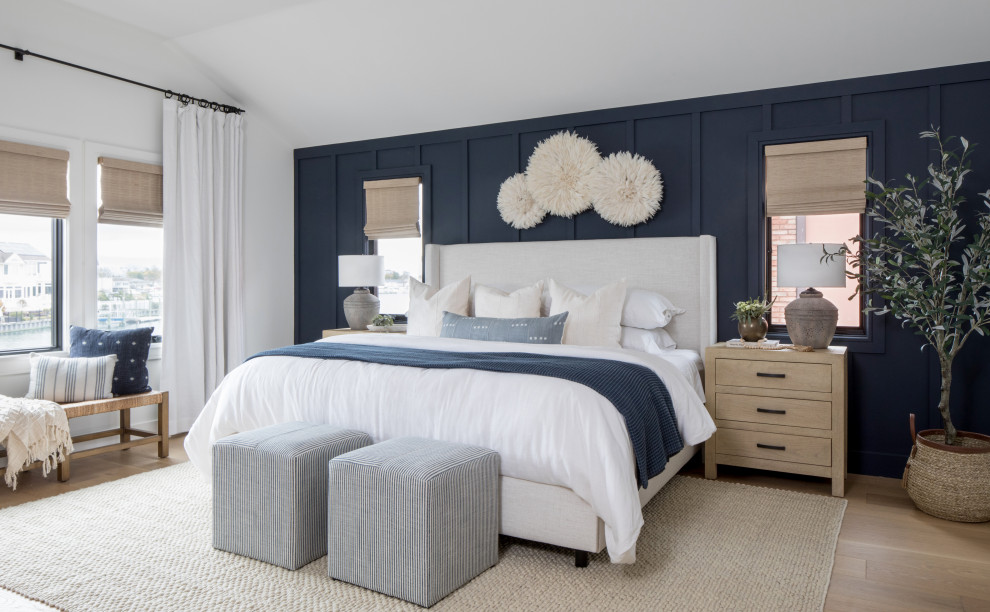 Mittelgroßes Maritimes Hauptschlafzimmer mit blauer Wandfarbe, braunem Holzboden und Wandpaneelen in New York
