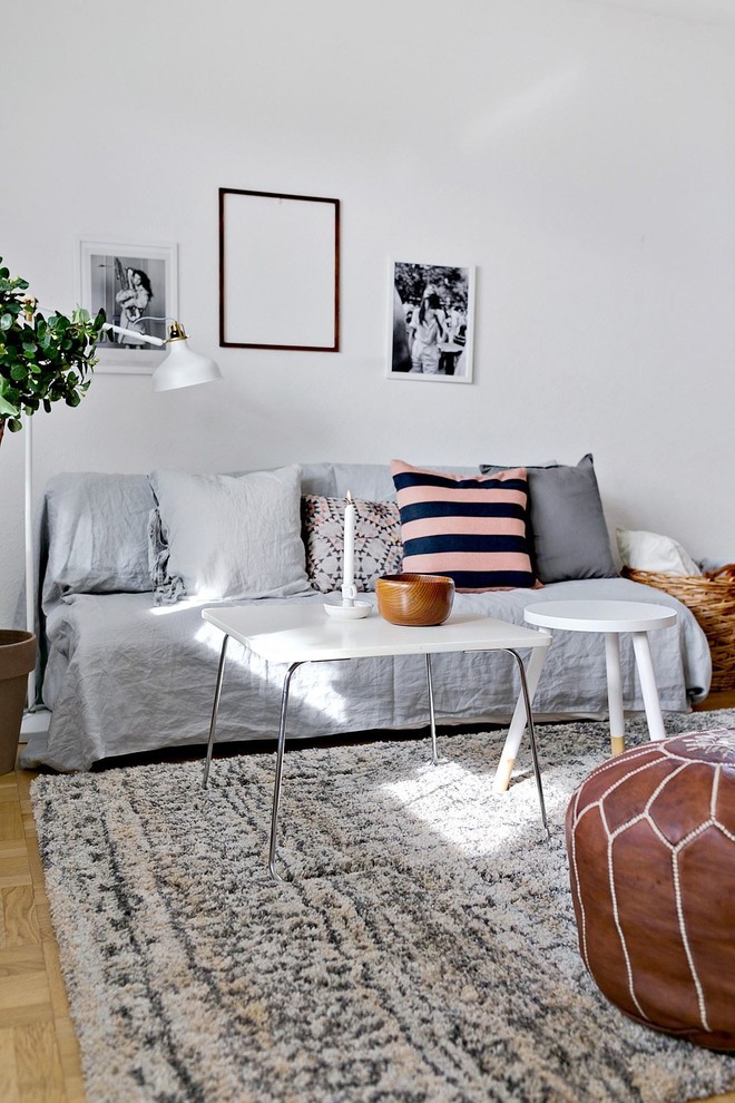 Photo of a scandinavian living room in Stockholm with white walls, light hardwood floors and no tv.
