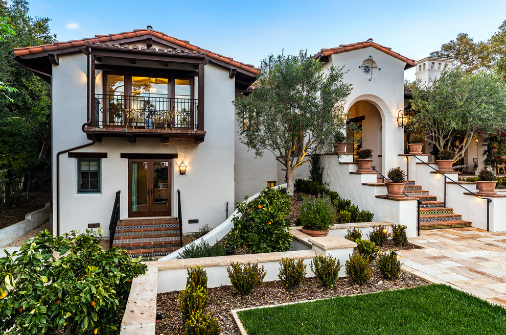 Large mediterranean two-storey stucco white house exterior in Santa Barbara with a gable roof and a tile roof.