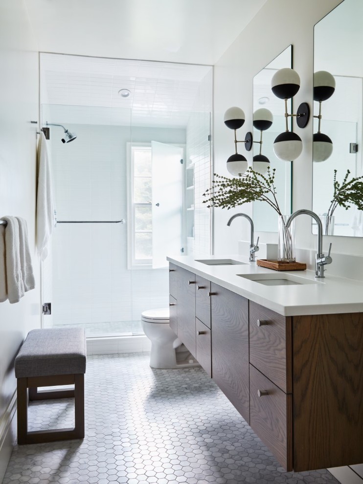 Mid-sized contemporary master bathroom in New York with flat-panel cabinets, medium wood cabinets, white tile, subway tile, white walls, mosaic tile floors, an undermount sink, engineered quartz benchtops, grey floor, a hinged shower door and white benchtops.