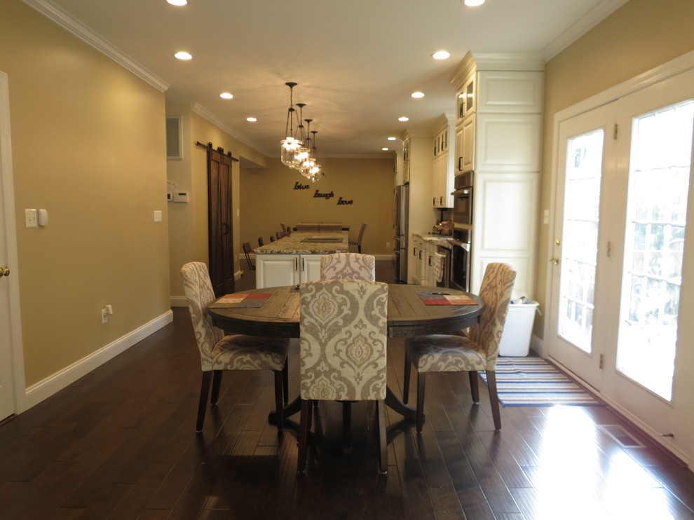 Example of a large transitional galley dark wood floor and brown floor dining room design with a double-bowl sink, raised-panel cabinets, white cabinets, granite countertops, white backsplash, porcelain backsplash, stainless steel appliances and an island