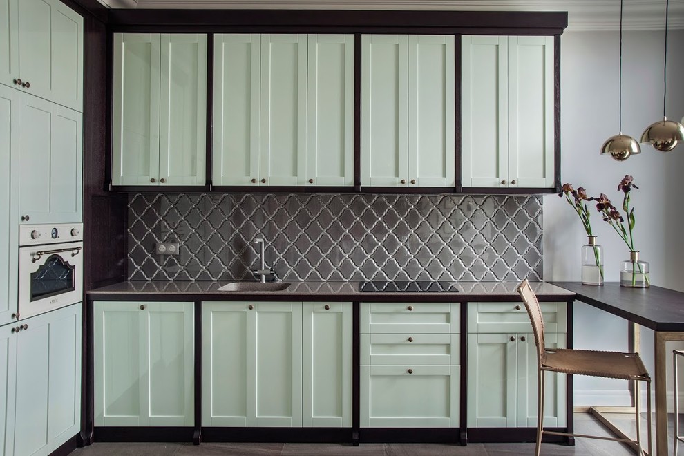Photo of a mid-sized traditional l-shaped kitchen in Other with green cabinets, an undermount sink, raised-panel cabinets, solid surface benchtops, grey splashback, ceramic splashback, coloured appliances, porcelain floors and no island.