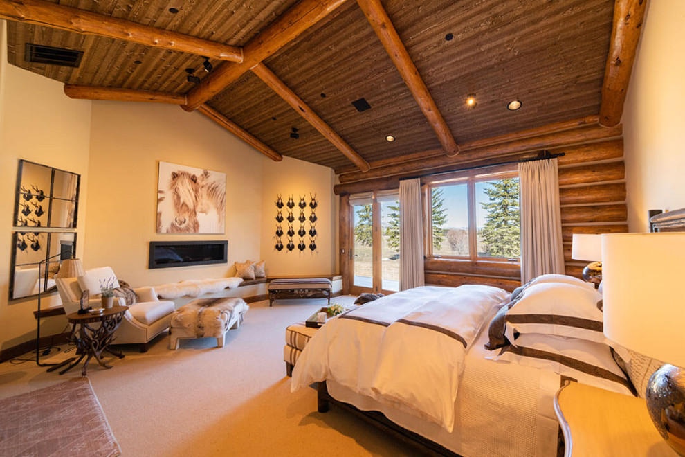 Imagen de dormitorio principal rural extra grande con paredes blancas, moqueta, todas las chimeneas, marco de chimenea de yeso, suelo beige, madera y madera