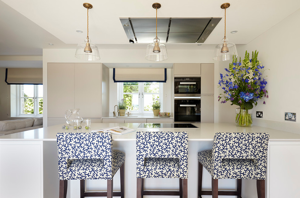 This is an example of a transitional galley kitchen in Channel Islands with flat-panel cabinets and a peninsula.