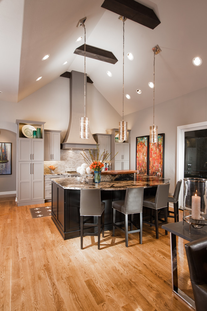 Example of a transitional kitchen design with shaker cabinets, gray cabinets, granite countertops, gray backsplash, stone tile backsplash and an island