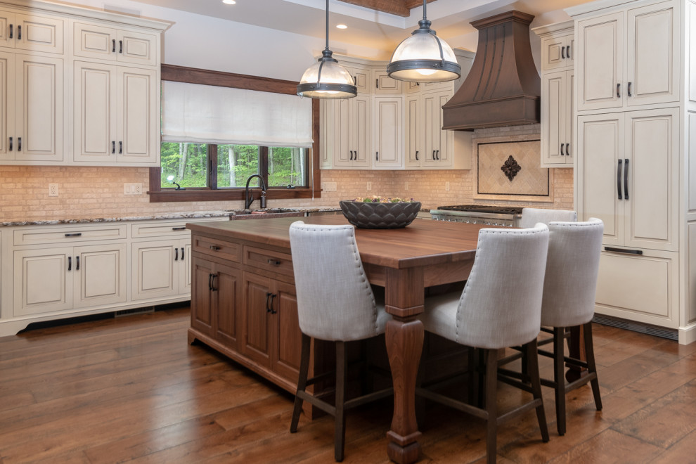 Photo of a country u-shaped eat-in kitchen in Other with a farmhouse sink, beige splashback, stainless steel appliances, medium hardwood floors, with island and brown floor.