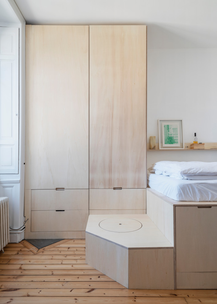 Diseño de dormitorio principal y blanco y madera nórdico pequeño con paredes blancas, suelo de madera en tonos medios y boiserie