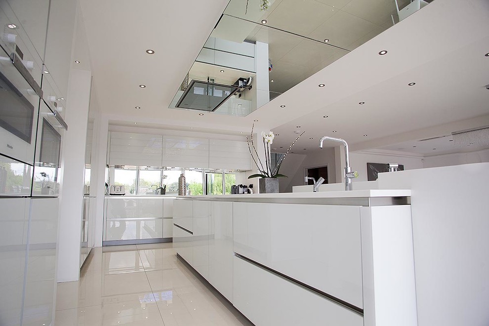 Photo of a large contemporary l-shaped eat-in kitchen in London with flat-panel cabinets, white cabinets, white appliances, porcelain floors and with island.