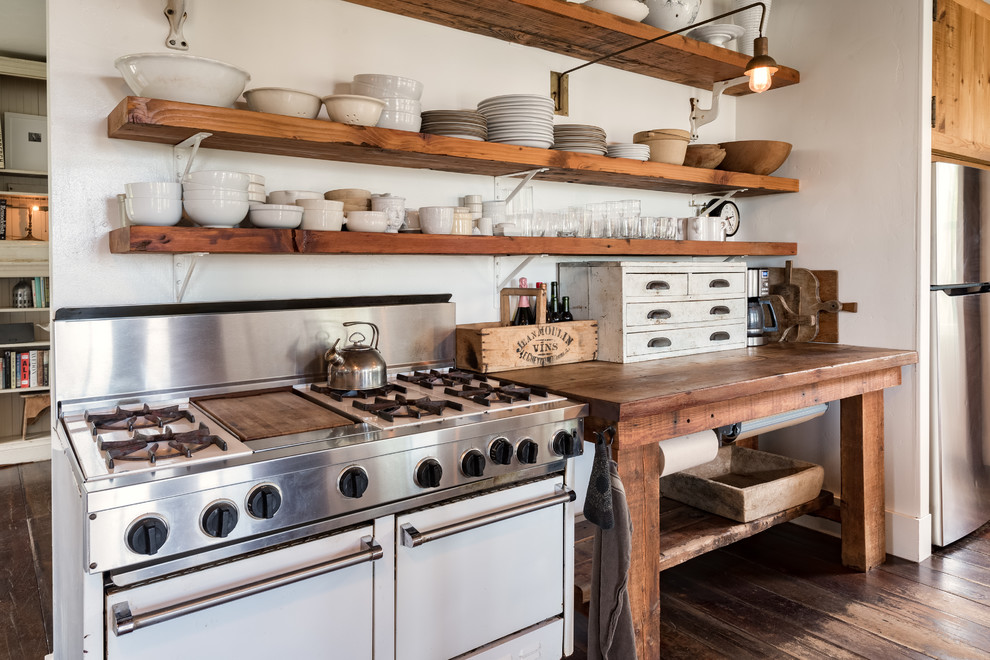 Country kitchen in San Francisco with open cabinets, medium wood cabinets, wood benchtops, white splashback, white appliances, dark hardwood floors, brown floor and brown benchtop.