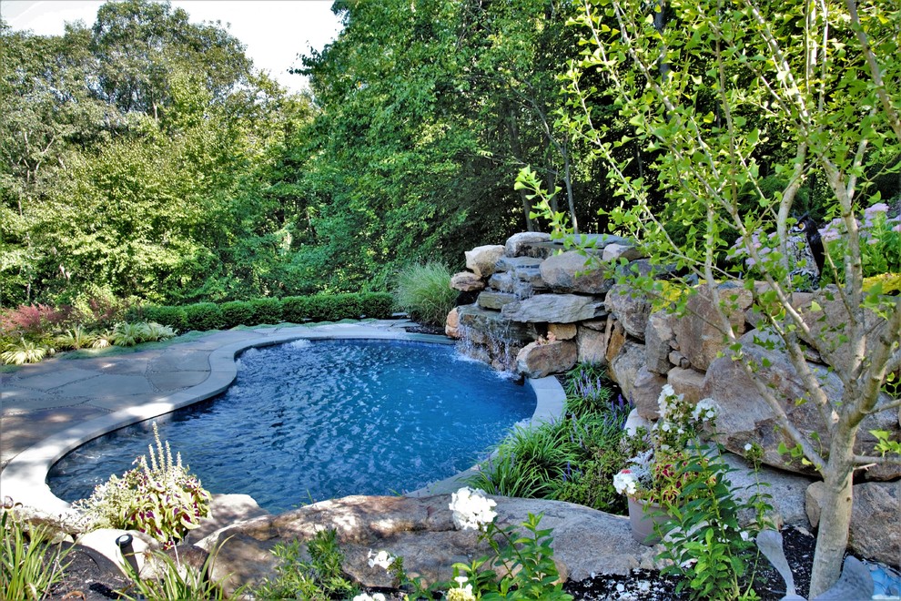 Small country backyard kidney-shaped natural pool in New York with a water feature and natural stone pavers.