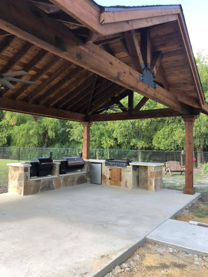 Large country backyard patio in Dallas with an outdoor kitchen, concrete slab and a gazebo/cabana.