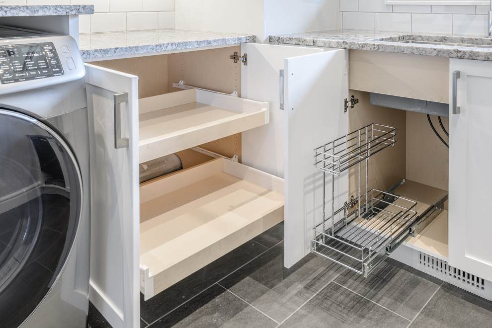 This is an example of a mid-sized contemporary l-shaped dedicated laundry room in Other with an undermount sink, recessed-panel cabinets, white cabinets, granite benchtops, grey walls, slate floors, a side-by-side washer and dryer, grey floor and multi-coloured benchtop.