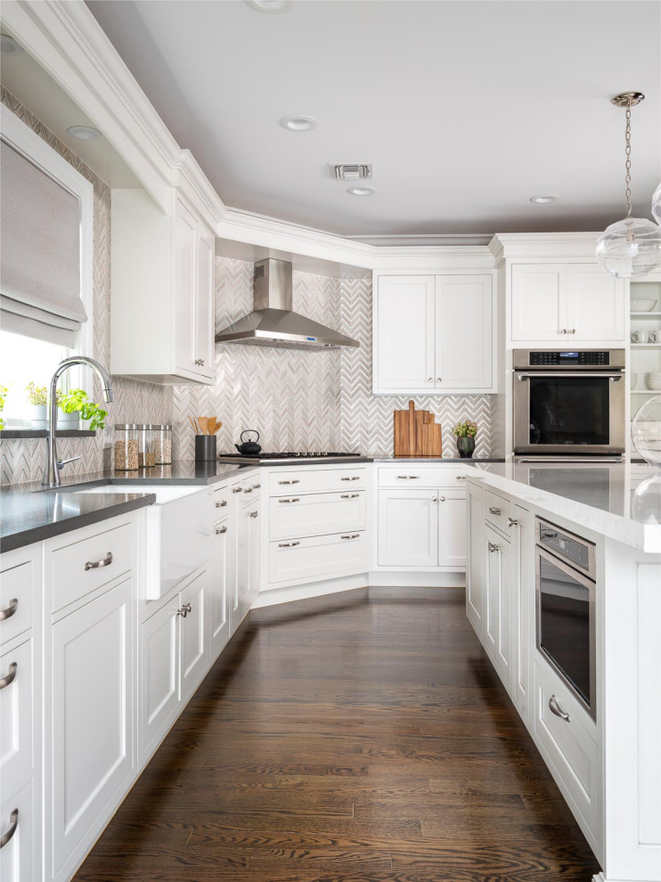 Large transitional l-shaped medium tone wood floor and brown floor eat-in kitchen photo in New York with a farmhouse sink, recessed-panel cabinets, white cabinets, quartz countertops, beige backsplash, porcelain backsplash, stainless steel appliances, an island and gray countertops