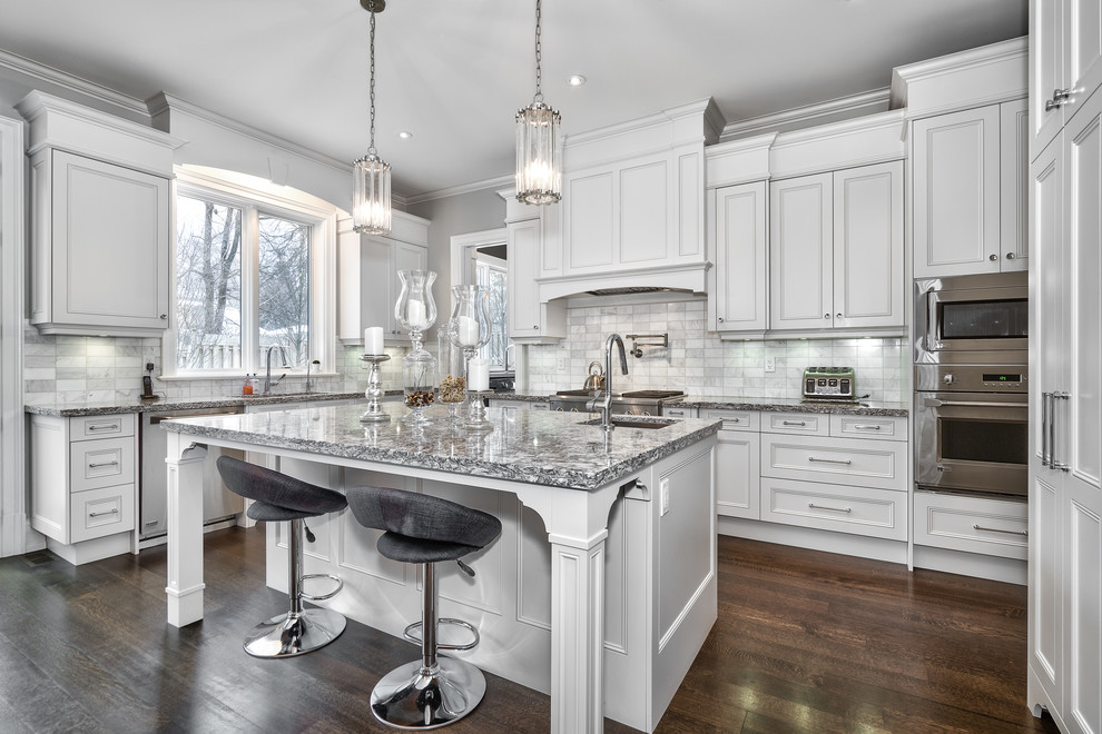 Open concept kitchen - large transitional u-shaped dark wood floor and brown floor open concept kitchen idea in Toronto with an undermount sink, beaded inset cabinets, white cabinets, granite countertops, gray backsplash, marble backsplash, paneled appliances, an island and multicolored countertops