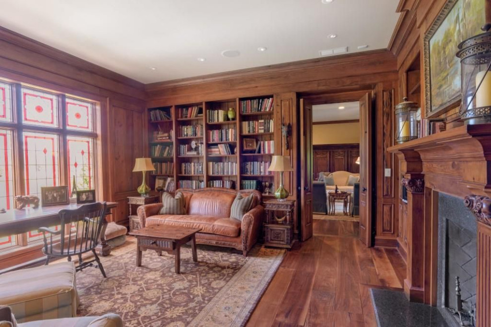 Large traditional home office in Atlanta with medium hardwood floors, a standard fireplace, a stone fireplace surround, a freestanding desk, brown floor and panelled walls.
