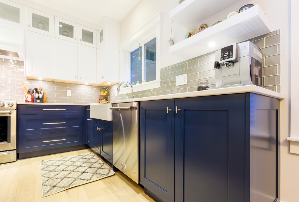 Inspiration for a large transitional u-shaped light wood floor open concept kitchen remodel with a farmhouse sink, shaker cabinets, blue cabinets, quartz countertops, gray backsplash, glass tile backsplash, stainless steel appliances, an island and white countertops