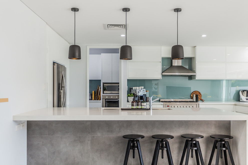 Design ideas for a contemporary kitchen in Perth with an undermount sink, flat-panel cabinets, blue splashback, glass sheet splashback, stainless steel appliances and a peninsula.