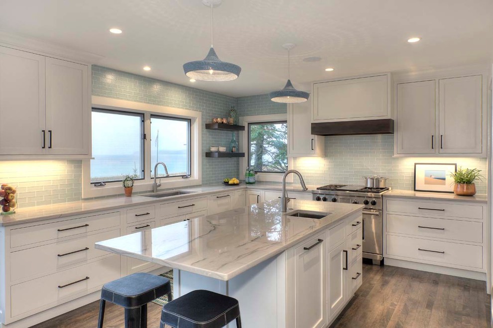 This is an example of a large beach style u-shaped eat-in kitchen in Chicago with a drop-in sink, shaker cabinets, white cabinets, marble benchtops, blue splashback, glass tile splashback, stainless steel appliances, medium hardwood floors and with island.