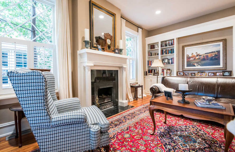 This is an example of a mid-sized traditional open concept family room in Richmond with a library, brown walls, dark hardwood floors, a standard fireplace, a wood fireplace surround, no tv and brown floor.