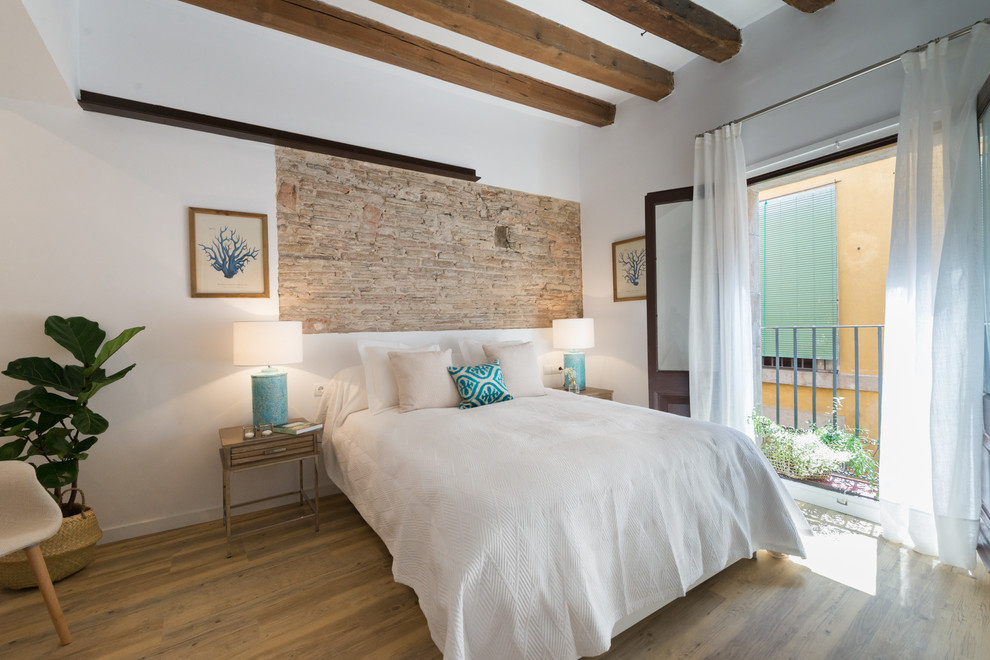 Design ideas for a mediterranean bedroom in Madrid with white walls, medium hardwood floors and brown floor.