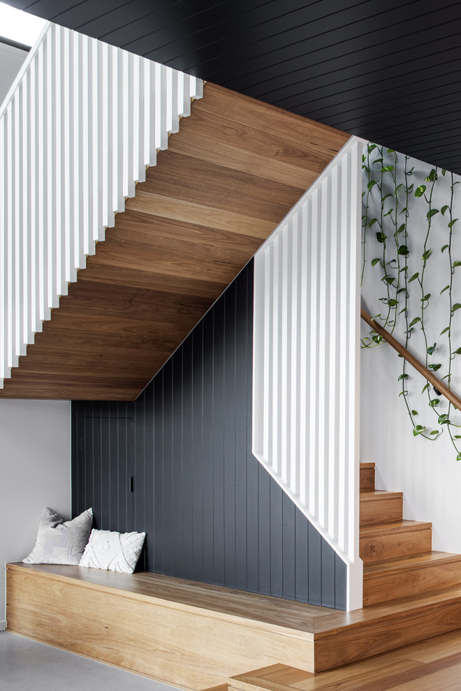 Trendy wooden wood railing and wall paneling staircase photo in Brisbane