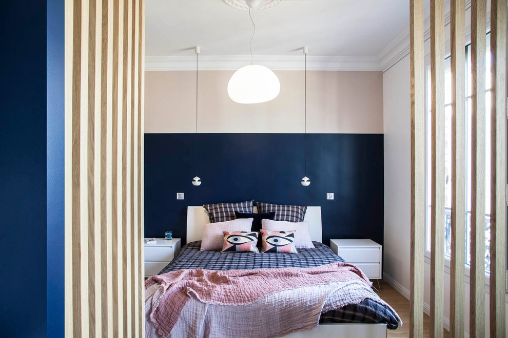 This is an example of a contemporary bedroom in Paris with pink walls, medium hardwood floors and brown floor.